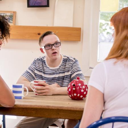 Afbeelding: een kleine diverse groep is in gesprek aan tafel