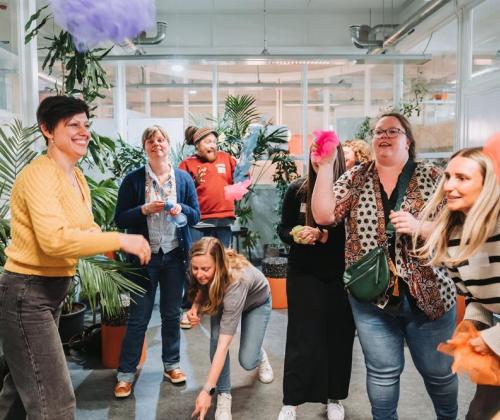 een groep deelnemers gooit gekleurde sjaaltjes naar elkaar